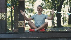 Portrait of a calm fitness man resting while sitting and meditating after yoga in park. Video footage in Ultra HD 4k video (3840x2160). Slow motion in 50/25fps