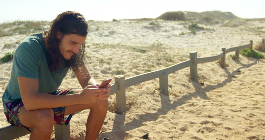 Happy man using mobile phone on the beach 4k