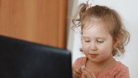 Child girl in headphones looks at the screen monitor computer