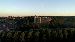 Drone descends slowly in front of Arundel Castle in the light of a summer dawn. Shot from Public Land