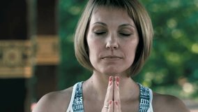 Portrait of a calm fitness woman resting while sitting and meditating after yoga in park. Video footage in Ultra HD 4k video (3840x2160). Slow motion in 50/25fps