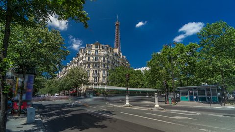 Eiffel Tower behind historic buildings in Paris timelapse hyperlapse, France. Blue cloudy sky at summer day with green trees and traffic on the street