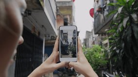 Close up of woman taking photo of Bangkok alley way street corner with smartphone in Thailand Asia. 