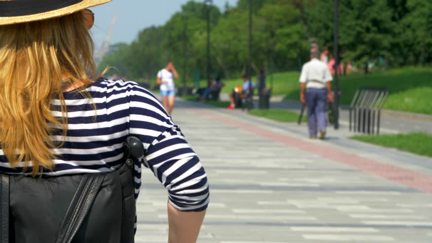 The invalid woman sit in the wheel chair and rides along the embankment