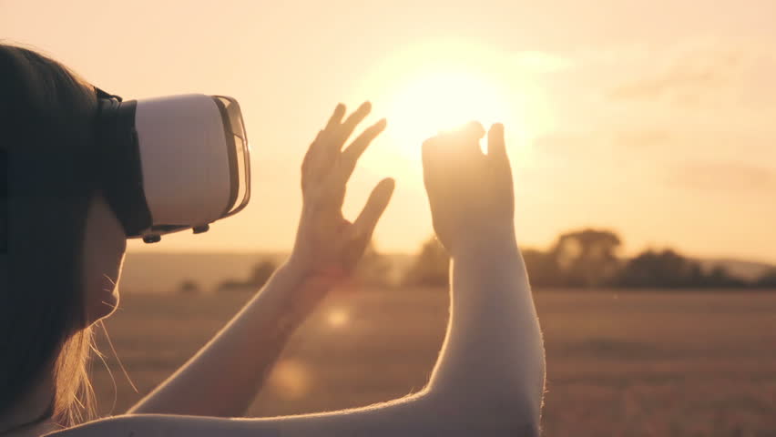 Beautiful girl in a golden wheat field uses virtual reality glasses in the sunset in slow motion | Shutterstock HD Video #1014442085