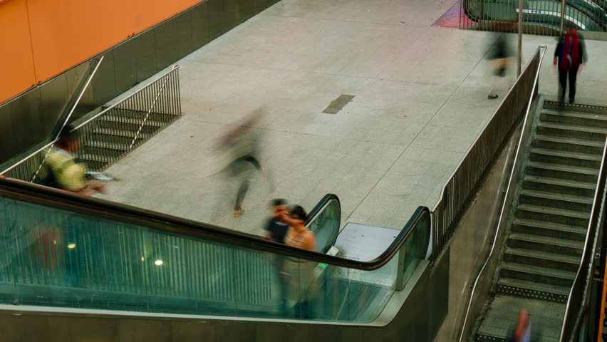 Time lapse of people walking on stairs and moving escalator at the interchange station near business and commercial center in Paris. Urban scene, city life, public transport hub and traffic concept. B