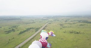 4K aerial video of hot air balloons taking off flying in green fields on cloudy morning near huge Plesheevo Lake in historical medieval town of Pereslavl-Zalessky north-east of Moscow, Russia