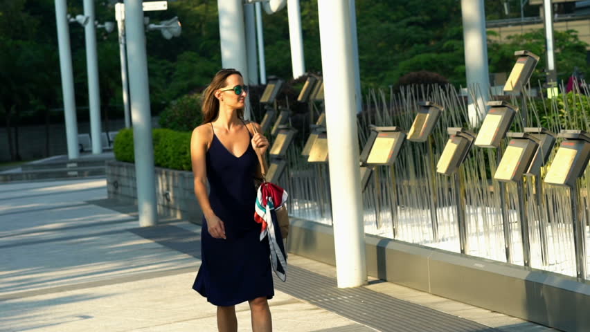 Confident beautiful woman walking in the city park, slow motion

