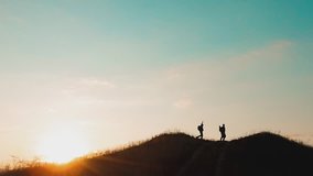 two men tourists hikers silhouette go to the mountains sunset travel slow motion video. Traveler successful young men walking on top of Mountain and waiting for sunrise lifestyle.