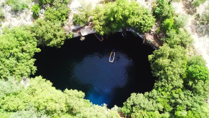 Aerial drone top view video of iconic open cave and lake of Melissani near port of Sami, Cefalonia island, Ionian, Greece
