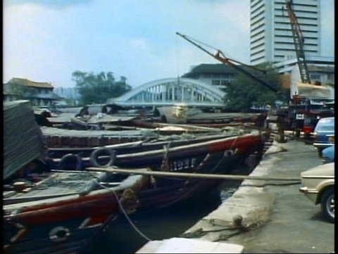 SINGAPORE, 1982, Singapore harbor, junks, old wooden boats, a crane lifts cargo