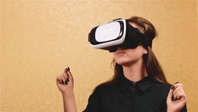 Beautiful young girl with long brown hair in a black suit in vr glasses. Future possibilities in home. Female looking video in vr glasses. Woman watch video or movie using modern virtual reality glass