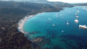 View from above, aerial view of a transparent and turquoise sea with some boats and yachts in front a beautiful beach. Emerald Coast, Sardinia, Italy.