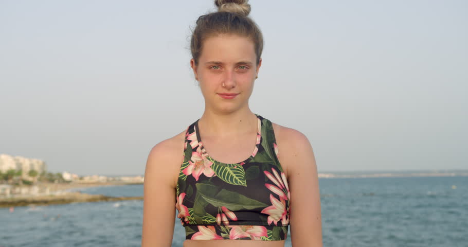 Young Pretty Blonde Girl Stood Smiling by Seaside Cliff. Active Beach Woman in Fitness Gym Clothes at Spanish Coastal Resort. Health and Wellbeing Female Student Tourist Outdoors in the Sun