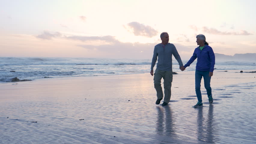 Senior couple walking at sunset on a sandy beach Royalty-Free Stock Footage #1014474704