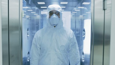 Scientist  Virologist  Factory Worker in Coverall Suit Disinfects Himself in Decontamination Shower Chamber. Biohazard Emergency Response. High Tech Research Pharmaceutical.