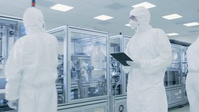 Quality Control Check: Scientist Using Digital Tablet Computer and wearing Protective Suit walks through Manufacturing Laboratory. Product Manufacturing: Pharmaceutics, Semiconductors, Biotechnology. - Powered by Shutterstock - Get 15% off with code: PIKWIZARD15