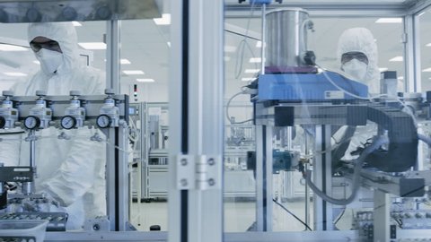 On a Factory Team of Scientists in Sterile Protective Clothing Work on a Modern Industrial 3D Printing Machinery. Pharmaceutical, Biotechnological and Semiconductor Manufacturing. Shot on RED EPIC 8K.
