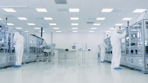 Team of Research Scientists in Sterile Suits Working with Computers, Microscopes and Modern Industrial Machinery in the Laboratory. Product Manufacturing Process. Shot on RED EPIC-W 8K Helium Camera.