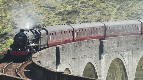 Glenfinnan, Scotland - May, 2018: View of Steam Train crossing Glenfinnan Viaduct Scotland, Pan Right