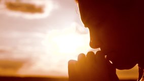 the girl prays. Girl folded her hands in prayer silhouette at sunset. slow motion video. Girl folded lifestyle her hands in prayer pray to God. girl praying asks forgiveness for sins of repentance