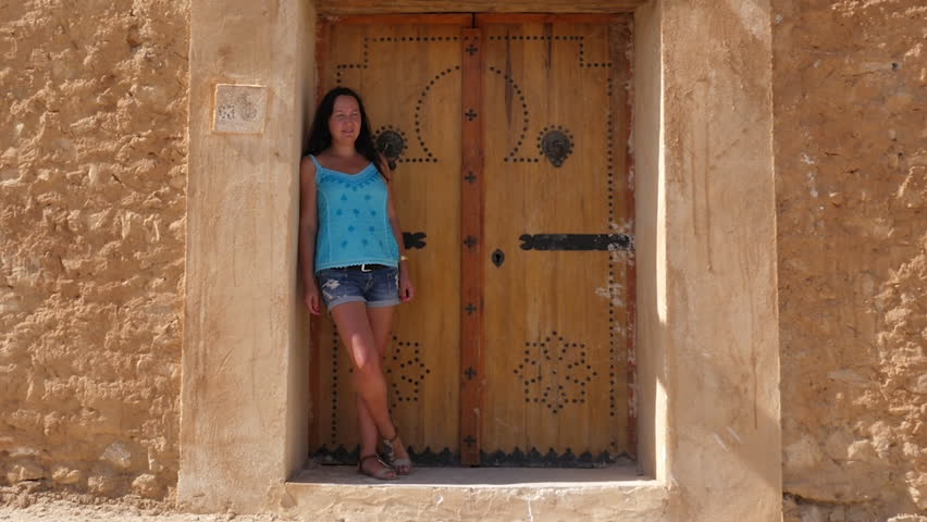 Young woman standing on background doors and rocky walls