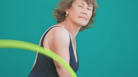 Handsome 60 years old women are smiling. She twists a Hula Hoop on her hand with great enthusiasm. Fitness process.  - Powered by Shutterstock - Get 15% off with code: PIKWIZARD15