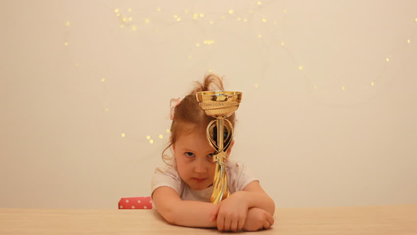 Child girl rejoices in the victory and reward, hugs the winner's cup for the first place in the championship competition. Royalty-Free Stock Footage #1014504659