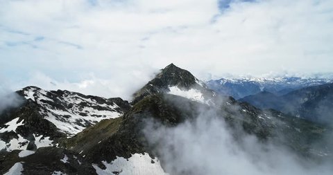 Forward aerial top view over cloudy rocky snowy mountain in sunny day with clouds.Italian alps mountains in summer with wild windy weather outdoor nature establisher.4k drone flight establishing shot 库存视频