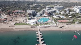 Hotel on the shore of the blue sea. Video. White sand, beautiful beach, tall palm trees. Vacation on the shore of the ocean. Aerial view