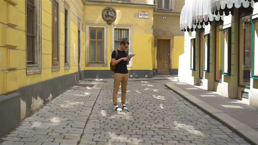 Man tourist with a city map in Vienna street. Caucasian boy looking with map of European city.