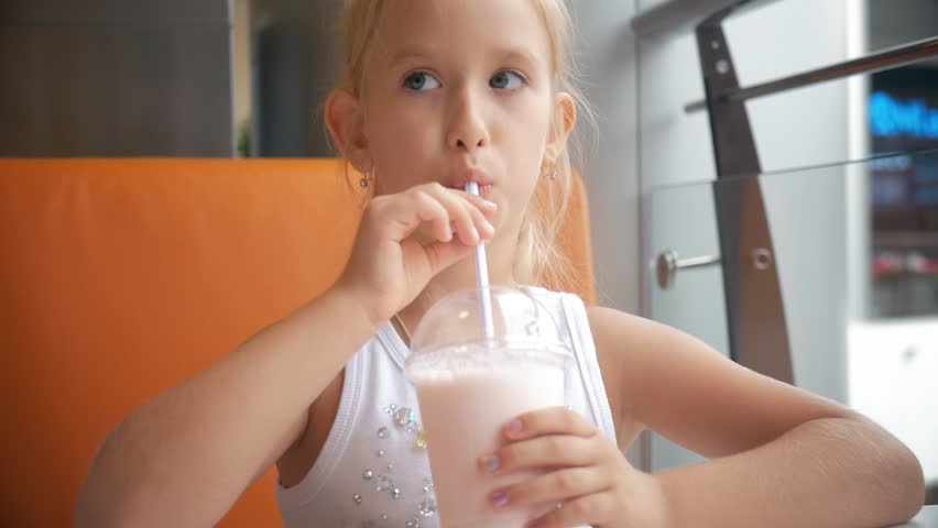 Little girl child in cafe drinking milk cocktail cacao with milk. Child drinks a milkshake sits in a cafe. | Shutterstock HD Video #1014520892