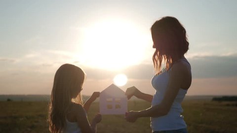Silhouette happy mother and daughter with dream house. Paper house as a symbol. The concept of family happiness. Arkivvideo