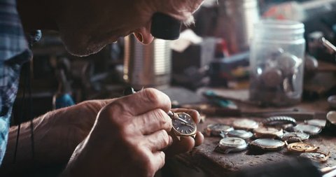 The old watchmaker is repairing the vintage hand watch in his workshop. RED camera shot. 4k footage.