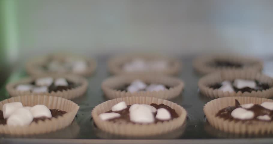 Closeup of delicious cupcakes with marshmallows on top inside oven home made sweets