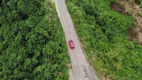 Ungraded cinematic overhead aerial view clip of a moving car on a road trip on a road near trees and nature