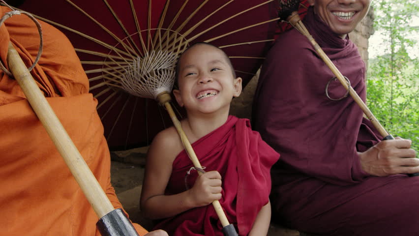 Authentic real monk boy holding bamboo umbrella smiling at camera In Bagan Mayanmar / Burma doing meditation in ancient temple. 
