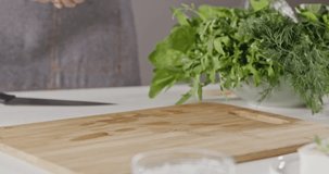 Background with tomatoes, greens, cheese, salt and pepper. Chef in an apron throwing her hands of red wet cherry tomatoes for cooking a salad. Panoramic slow motion. Full HD video, 240fps,1080p