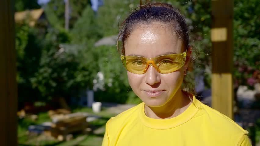 portrait. cute woman Builder in yellow tank top and safety glasses. smiles