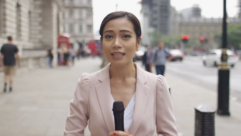 Asian news reporter reporting to camera in the city