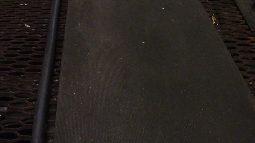 Panning up wooden cat-walk on iron grating floor between wooden tubs