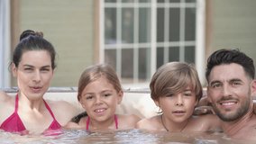 Family of 4 enjoying bath in spa hot tub