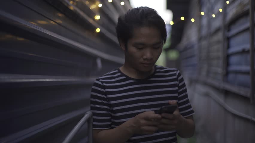 Handsome Asian young man with smartphone at outside during evening