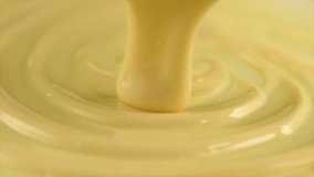 White Chocolate. Pouring melted liquid premium milk white chocolate. Close up of molten liquid hot chocolate swirl. Confectionery. Confectioner prepares dessert, icing. 4K UHD video, slow motion