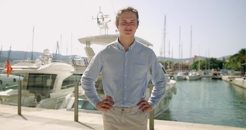Handsome Rich Young Man Stood in front of his Millionaire Yachts Successful Business Man Gesturing What he owns in the Lovely Spanish Palma City. Wealthy billionaire happy and enjoying money. 