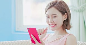 woman sit on sofa and use phone happily at home