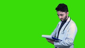 Standing doctor wears the white coat holding clipboard checking the work on green Chroma.