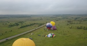 4K aerial video of hot air balloons taking off flying in green fields on cloudy morning near huge Plesheevo Lake in historical medieval town of Pereslavl-Zalessky north-east of Moscow, Russia