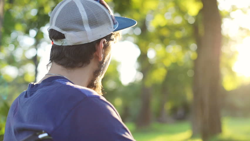 unidentified young man in a wheelchair enjoying nature beauty and looking at sun setting over the horizon summer rest health care disease prevention physical recovery paralyzed body disability pension