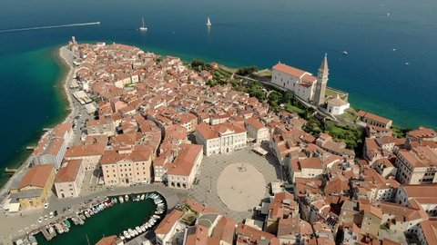Beautiful aerial footage of Piran town with Tartini main square, ancient buildings with red roofs and Adriatic sea in southwestern Slovenia.
